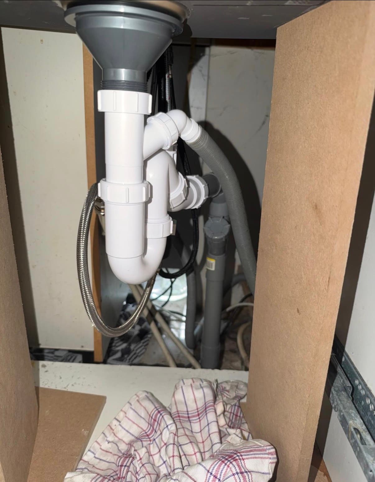 Nieuwe sifon en afvoer onder een gootsteen, met aansluiting voor de vaatwasser