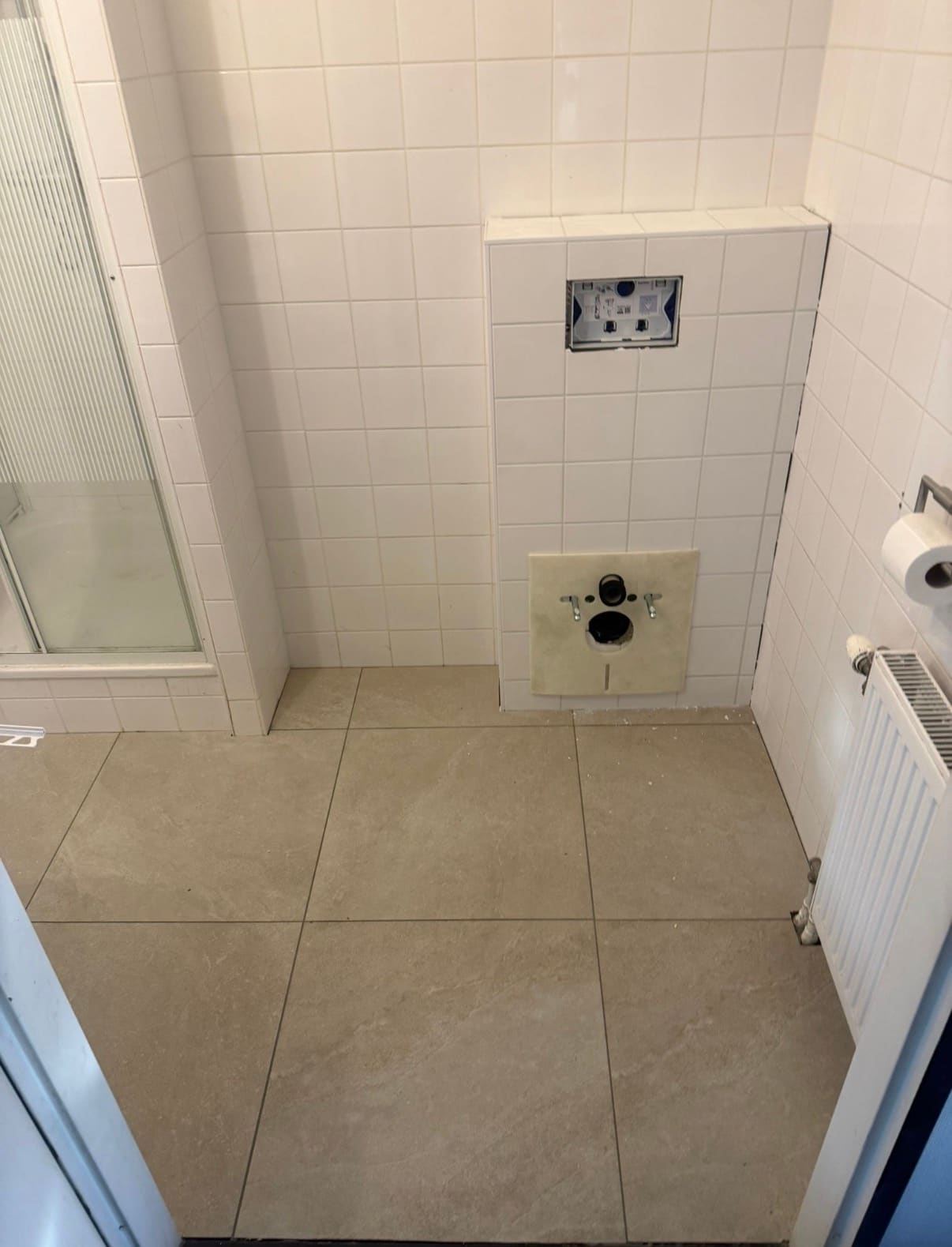 Betegelde toiletwand met inbouwreservoir en radiator