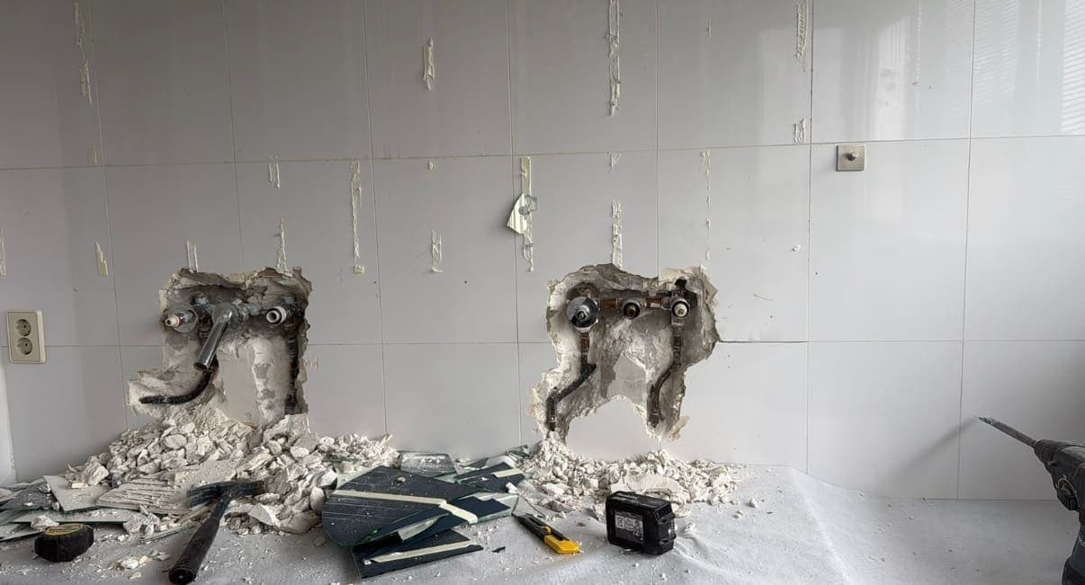 Opengehakte wand met nieuwe water- en afvoerleidingen