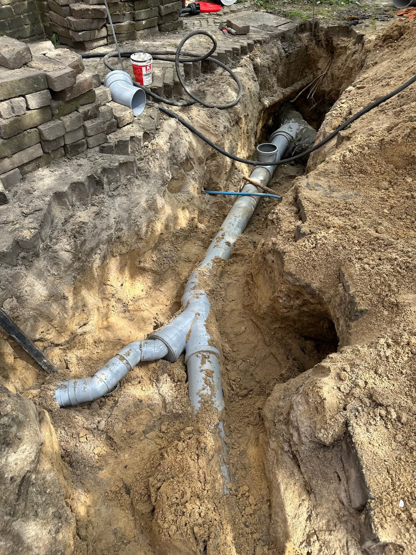 Nieuwe pvc-rioolleiding met aftakkingen in een open sleuf in de tuin